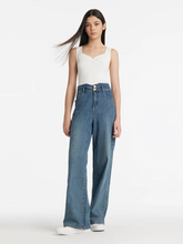 a lady in white tank top with loose fit jeans